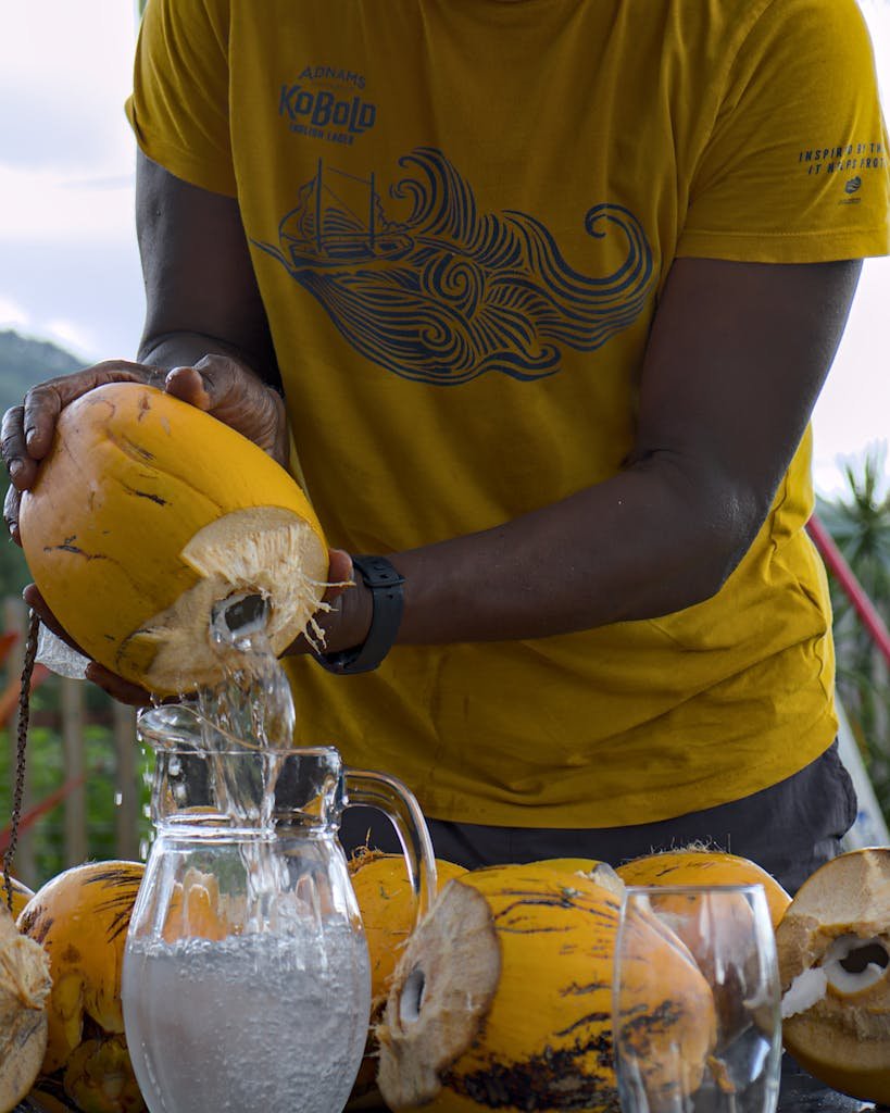 Refreshing coconut water being poured from a coconut into a glass jug in Trinidad and Tobago.