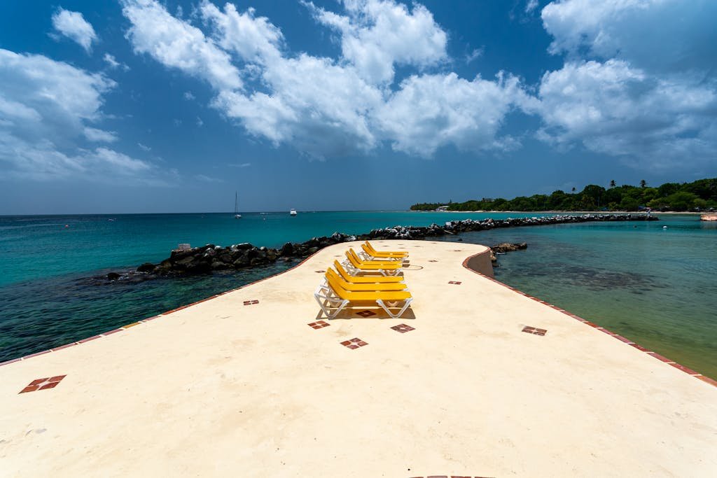 Relaxing beach scene with yellow chairs on a pier in Tobago, perfect for a tropical vacation.