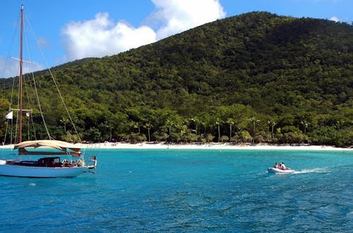 Scenic view of a sailboat and motorboat near the shore of St. John's lush beaches, perfect for a tropical vacation.