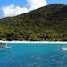 Scenic view of a sailboat and motorboat near the shore of St. John's lush beaches, perfect for a tropical vacation.