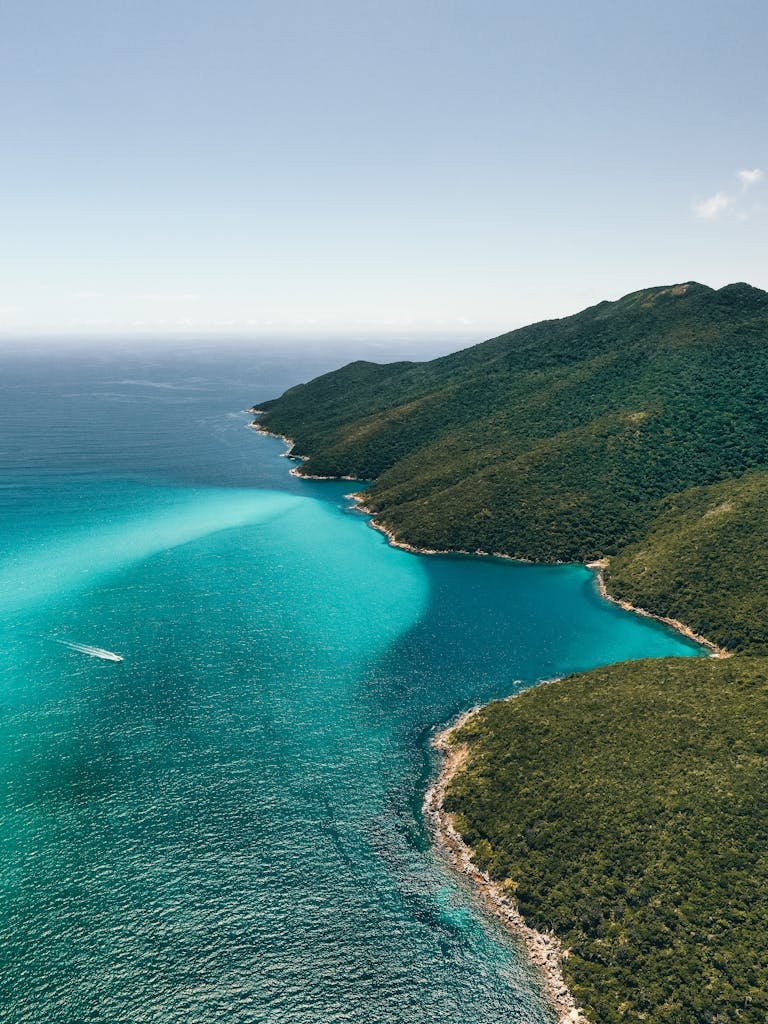 Stunning aerial shot of Arraial do Cabo's turquoise waters and lush landscapes on a sunny day.