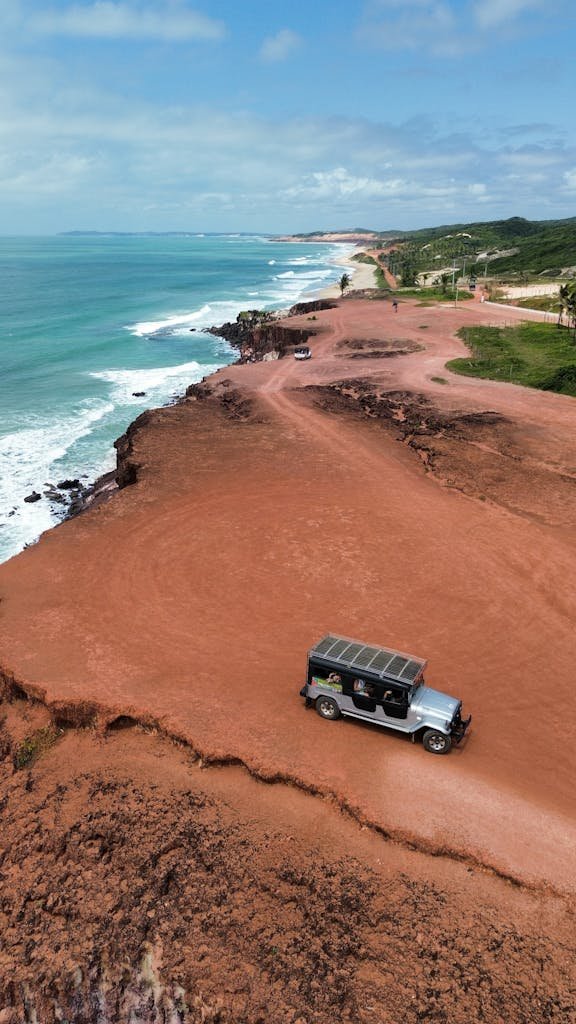 A breathtaking aerial view of the rugged coastline at Praia da Pipa, showcasing the vibrant red sandstone cliffs and ocean.