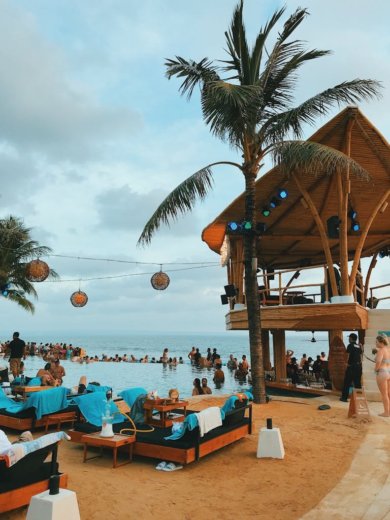 A bustling beach resort scene in Bali with an oceanfront pool and vibrant atmosphere.