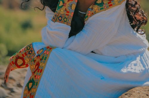 A smiling Ethiopian woman in traditional attire enjoying a sunny day outdoors, captured in Addis Ababa.