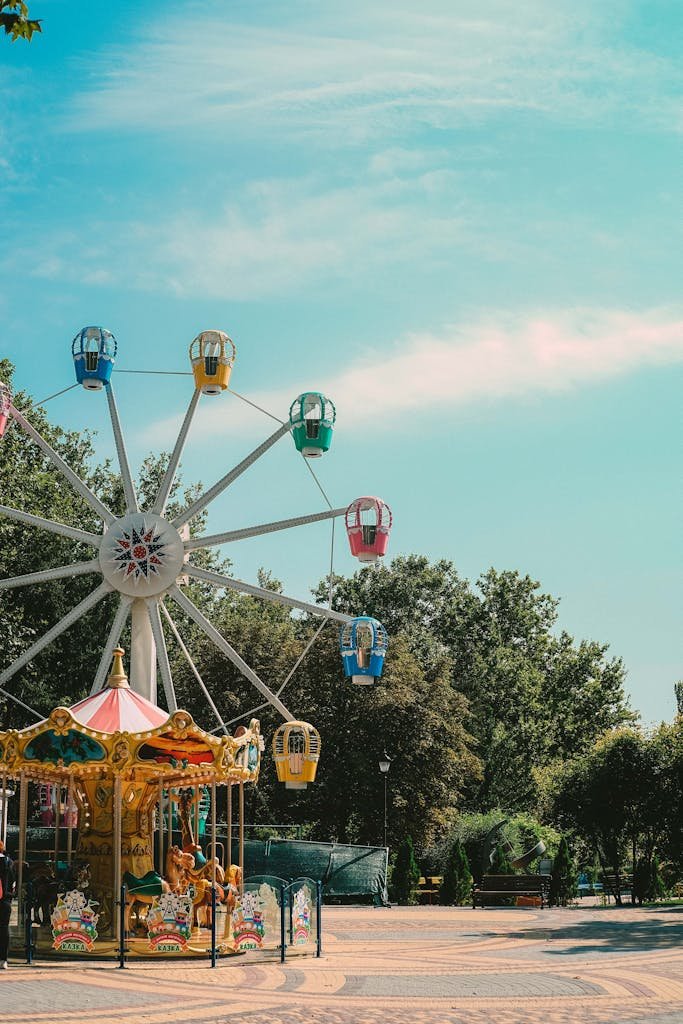 A vibrant Ferris wheel stands against a blue sky in a sunny amusement park.