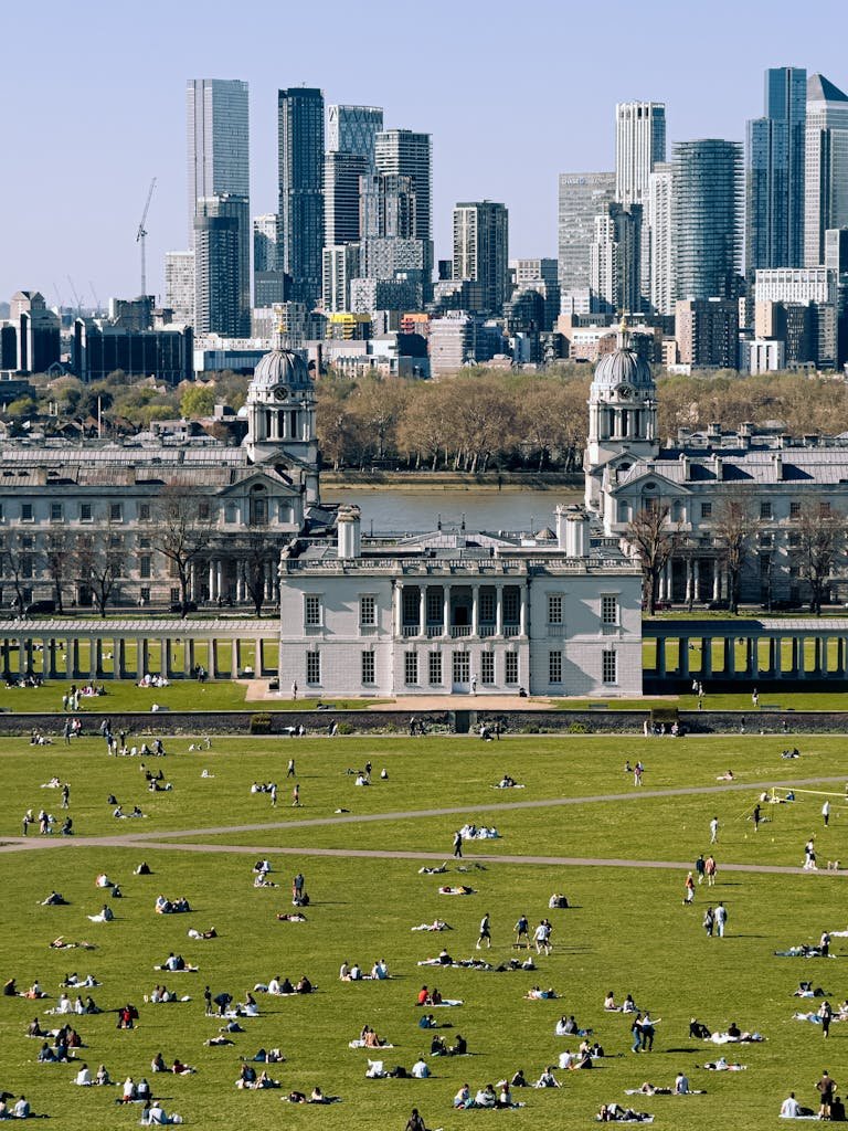A vibrant scene of people enjoying Greenwich Park with London's skyline in the background.