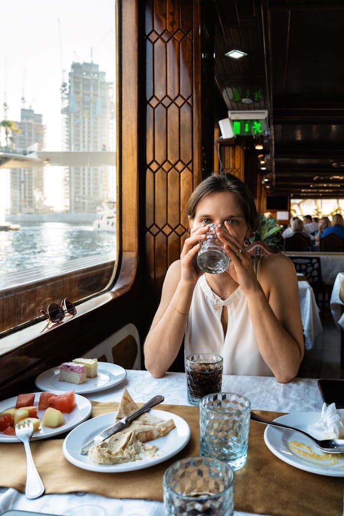 A woman enjoying a meal on a boat in Dubai Marina, featuring waterfront views.
