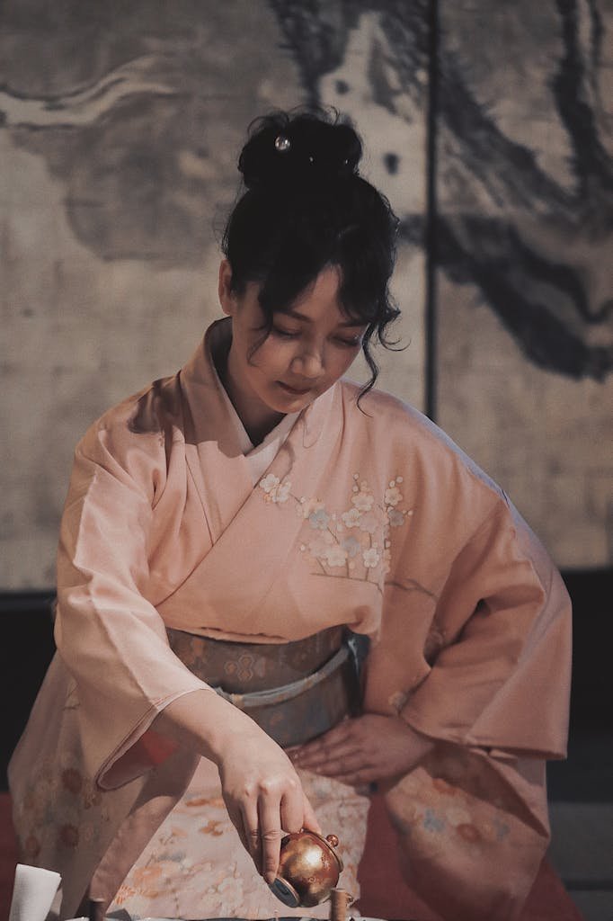 Asian woman in traditional kimono elegantly pouring tea, showcasing Japanese culture.