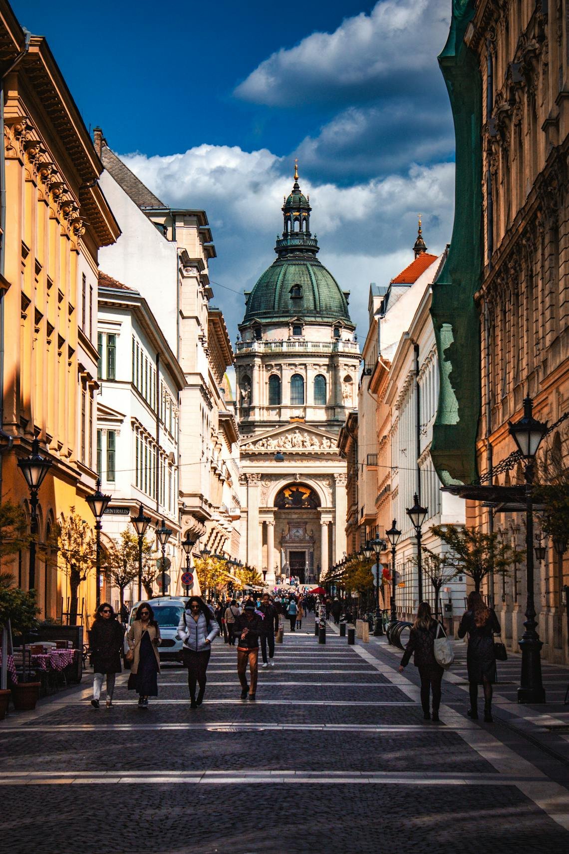 Bustling street view leading to the iconic St. Stephen's Basilica in vibrant Budapest on a sunny day.