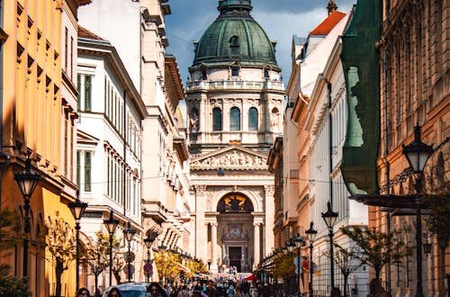 Bustling street view leading to the iconic St. Stephen's Basilica in vibrant Budapest on a sunny day.
