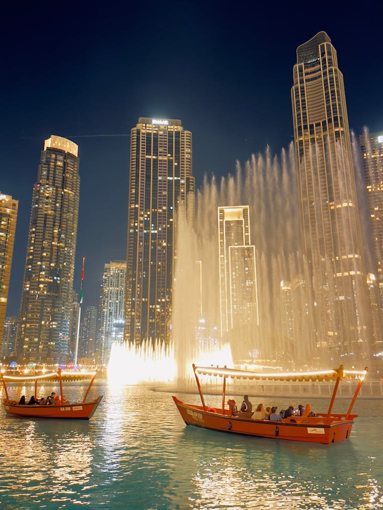 Captivating night view of Dubai's iconic fountain show with traditional boats and skyscrapers.