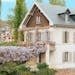 Charming house with wisteria in bloom beside a canal, showcasing classic French architecture.