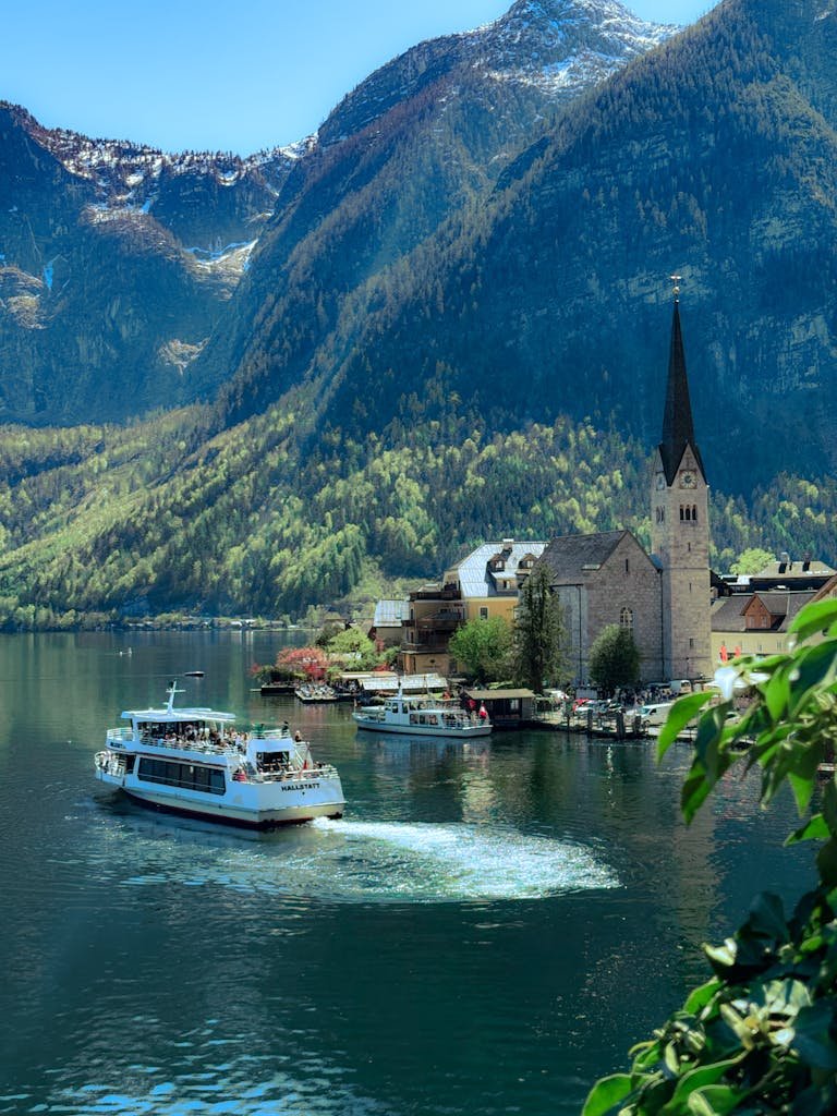 Charming scene of Hallstatt village and church by the lake with a backdrop of stunning Alpine mountains.