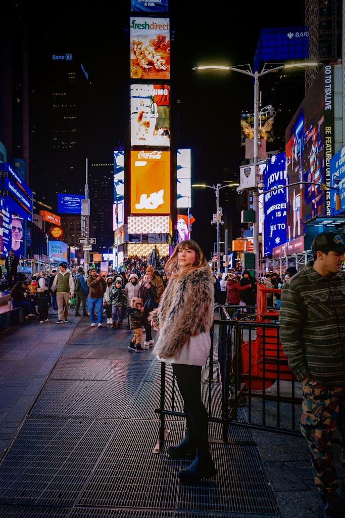 Chic woman in faux fur amidst vibrant Times Square, New York City at night.