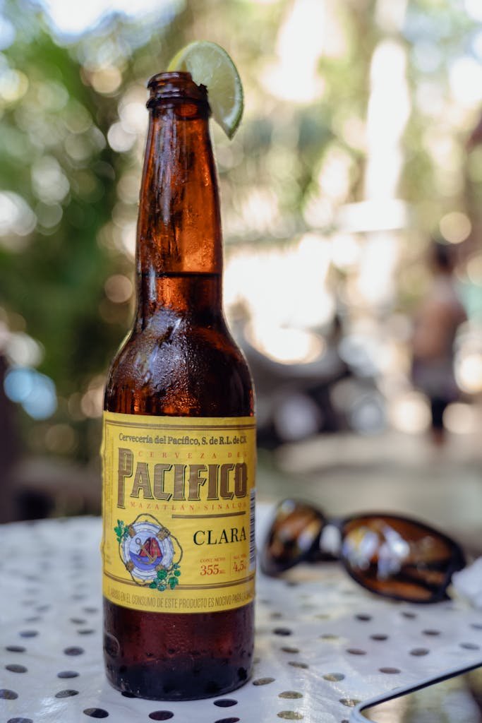 Chilled Pacifico beer bottle with lime outdoors on a sunny day, perfect for relaxation.