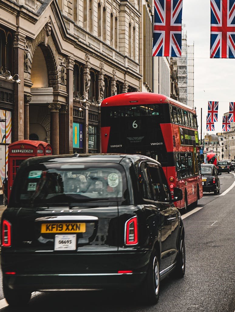 Classic London street scene featuring a red double-decker bus, black taxi, and UK flags, capturing the city's urban essence.