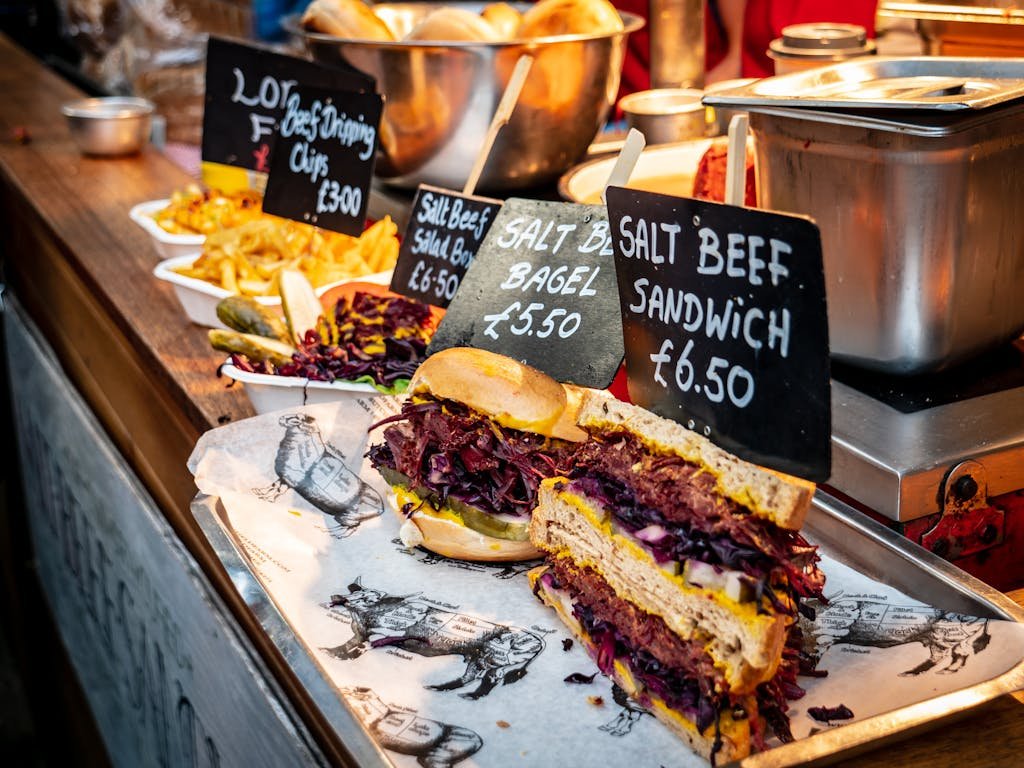 Close-up of a delicious salt beef sandwich on display at a bustling London market street food stall.