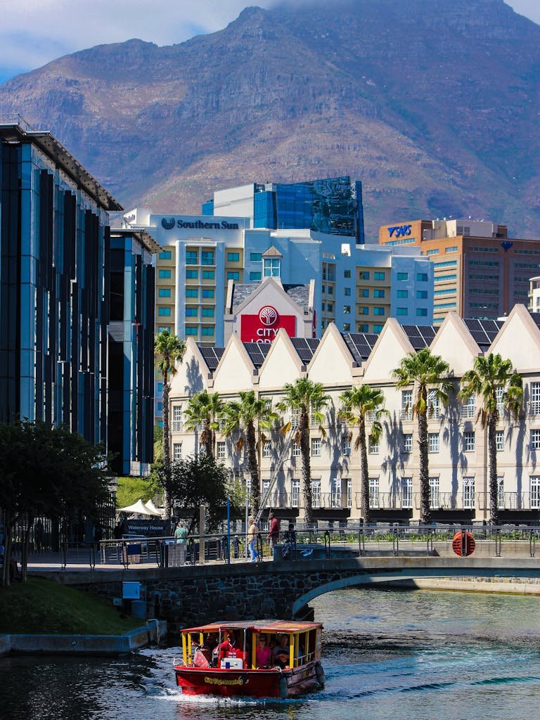 Colorful boat on a canal with modern buildings and mountains in Cape Town.