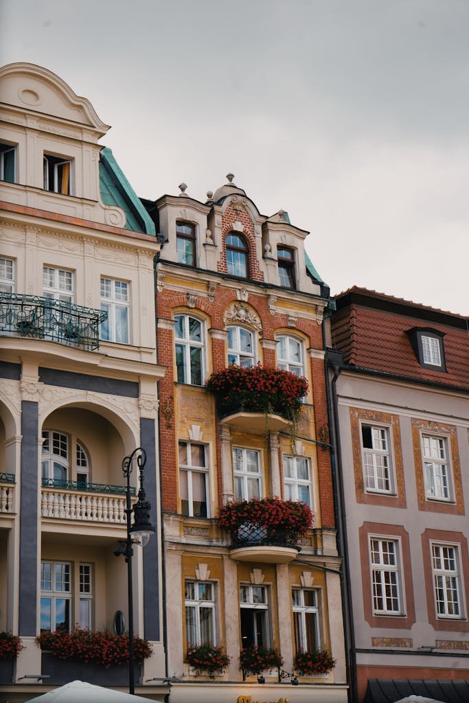 Colorful European buildings with flower-adorned balconies under cloudy skies.