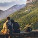 Couple sitting together enjoying a scenic mountain view at sunset, embodying love and adventure.