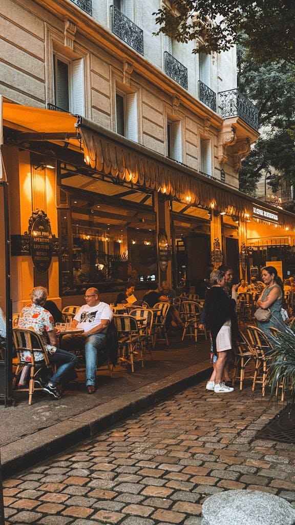 Cozy outdoor seating at a Parisian cafe with warm lighting, capturing the essence of evening leisure in Paris.