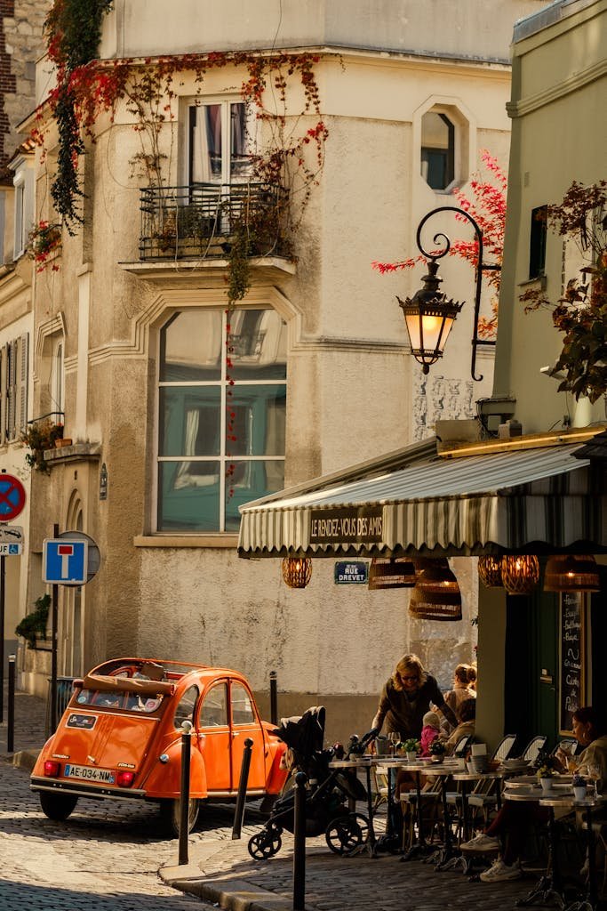 Cozy Paris street with outdoor café and vintage orange car on a sunny day.
