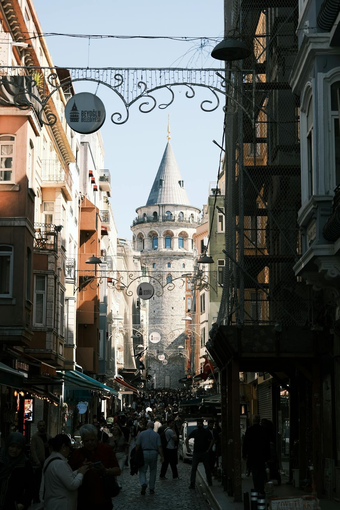 Crowded street view towards the historic Galata Tower in Istanbul, showcasing vibrant urban life.