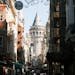 Crowded street view towards the historic Galata Tower in Istanbul, showcasing vibrant urban life.
