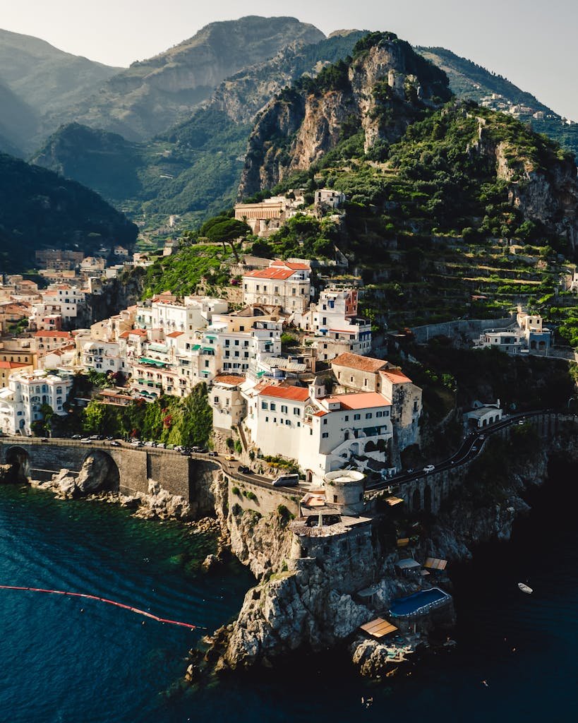 Drone shot of a picturesque coastal town on the Amalfi Coast, Italy, against a backdrop of mountains.
