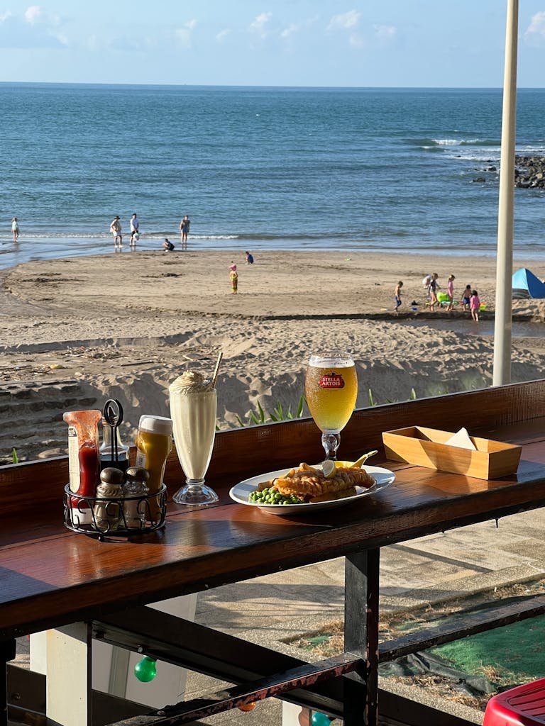 Enjoy a relaxed meal with fish and chips, milkshake, and beer by the beach.
