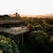 Explore a tranquil treehouse retreat surrounded by lush greenery at sunset, ideal for a relaxing getaway.