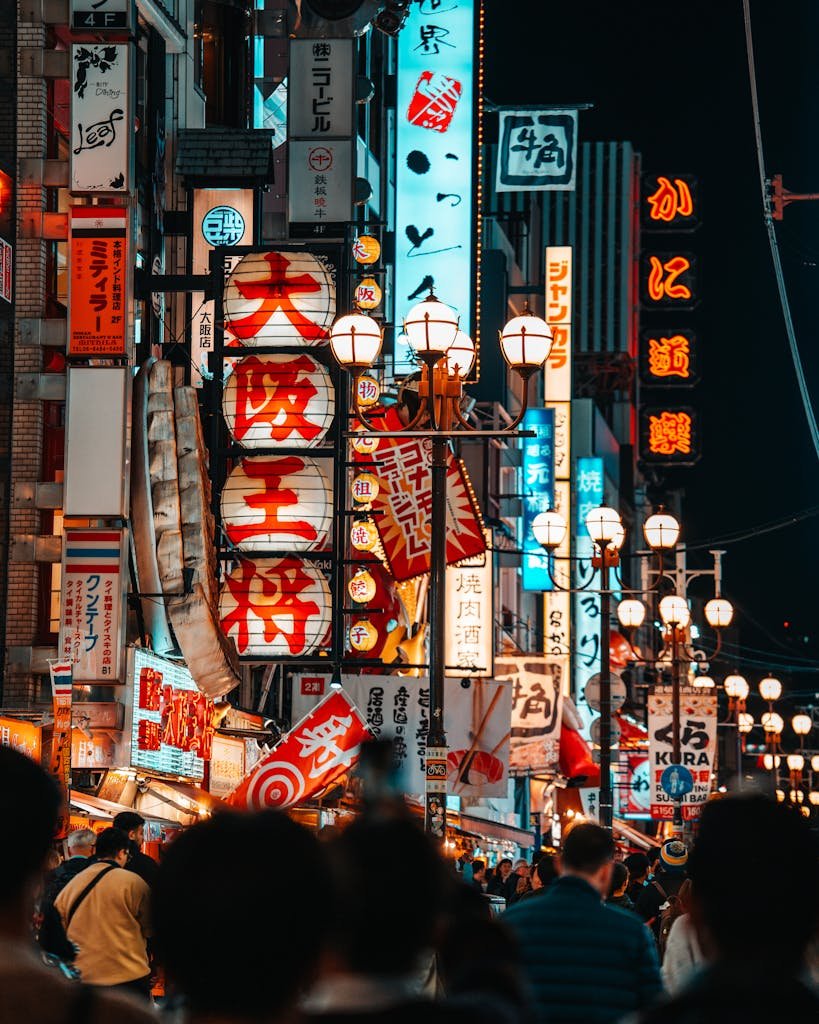 Explore the vibrant nightlife of Osaka's Dotonbori district with bustling crowds and bright neon signs.