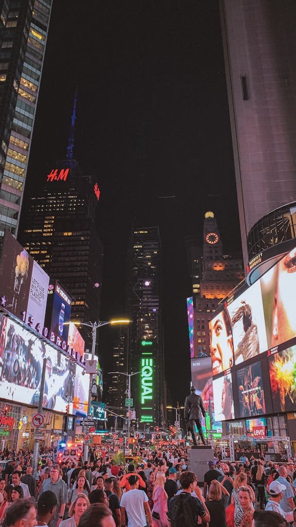 Lively crowd and bright billboards in Times Square, New York City at night, showcasing NYC's iconic urban vibe.