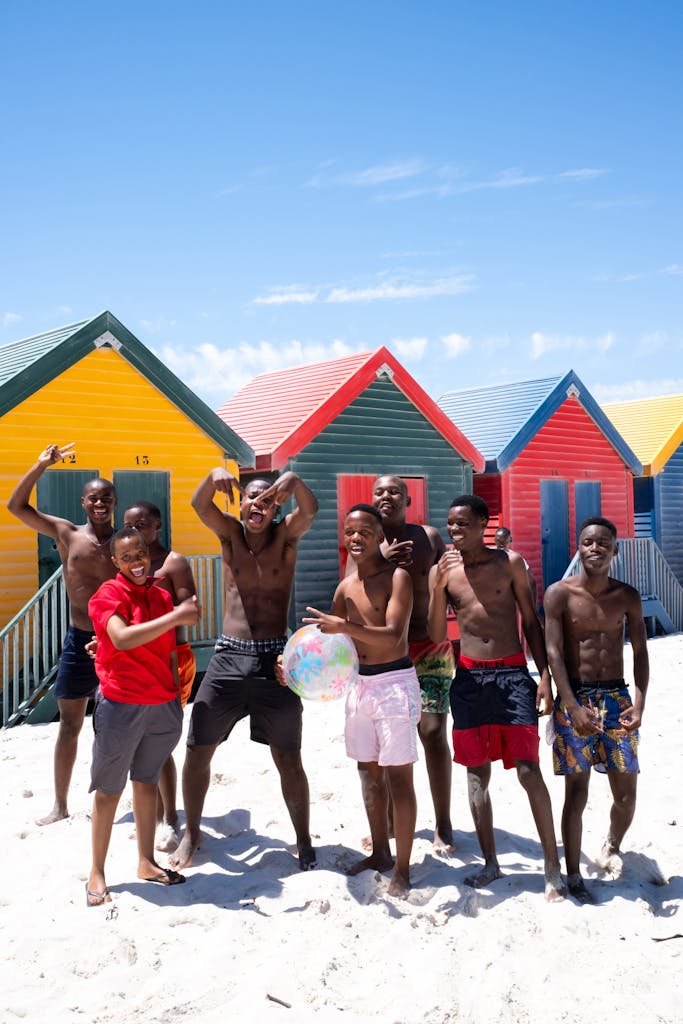 Lively group of friends having fun at colorful beach huts on a sunny day outdoors.