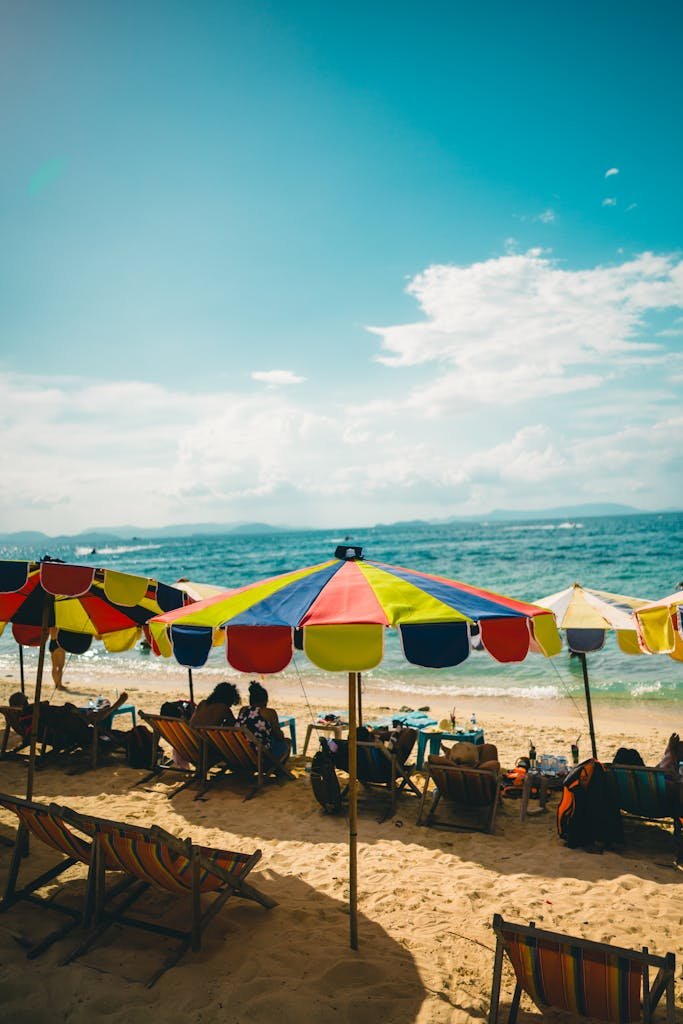 Relaxing day by the vibrant beach in Phuket, Thailand with colorful umbrellas and sun loungers.