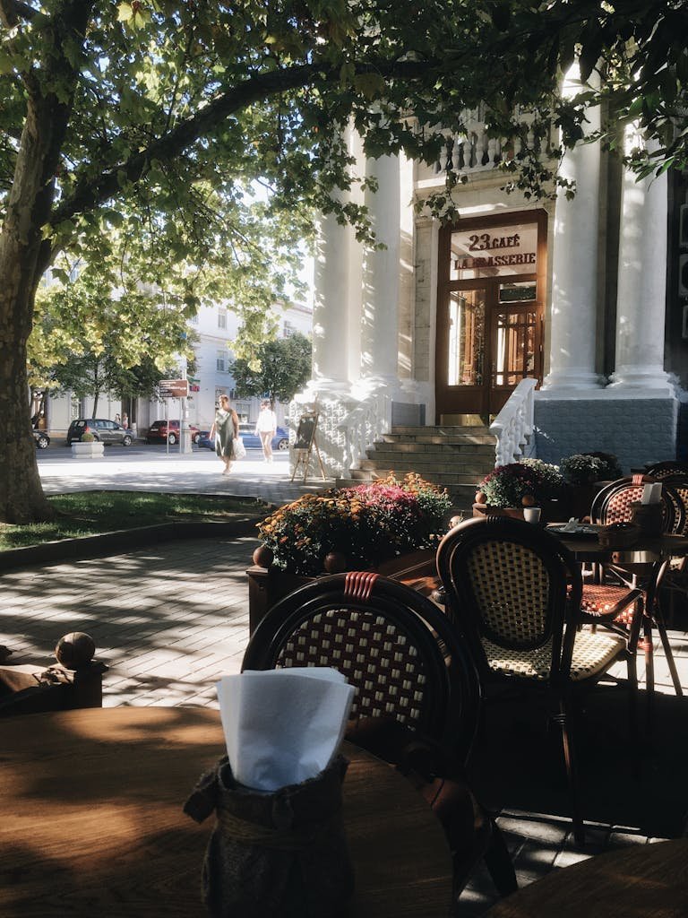 Round wooden tables and weaved chairs placed on paved street in cozy outdoors cafe on sunny day