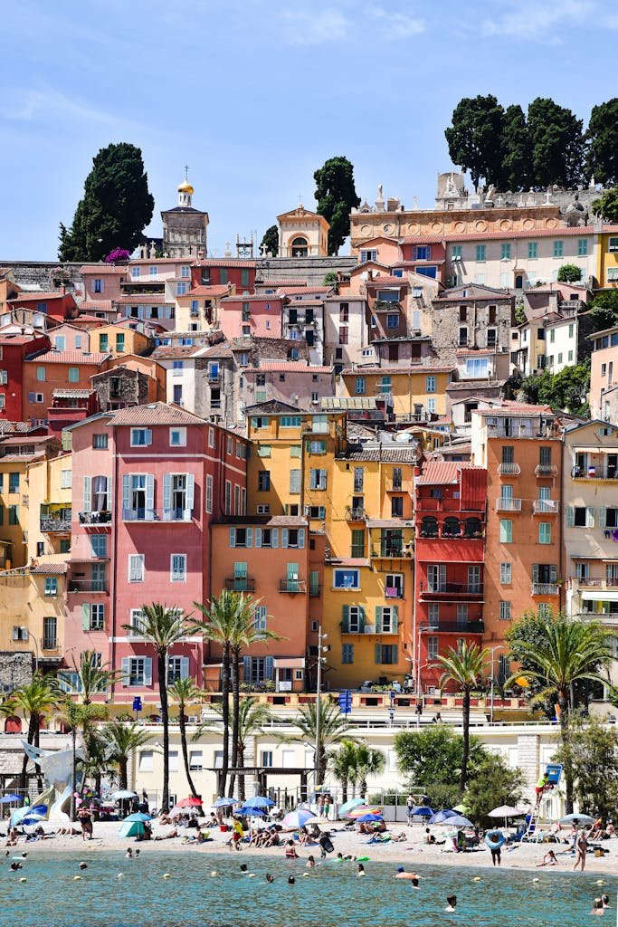 Vibrant architecture in Menton, France with beachgoers enjoying the sunny coastline.