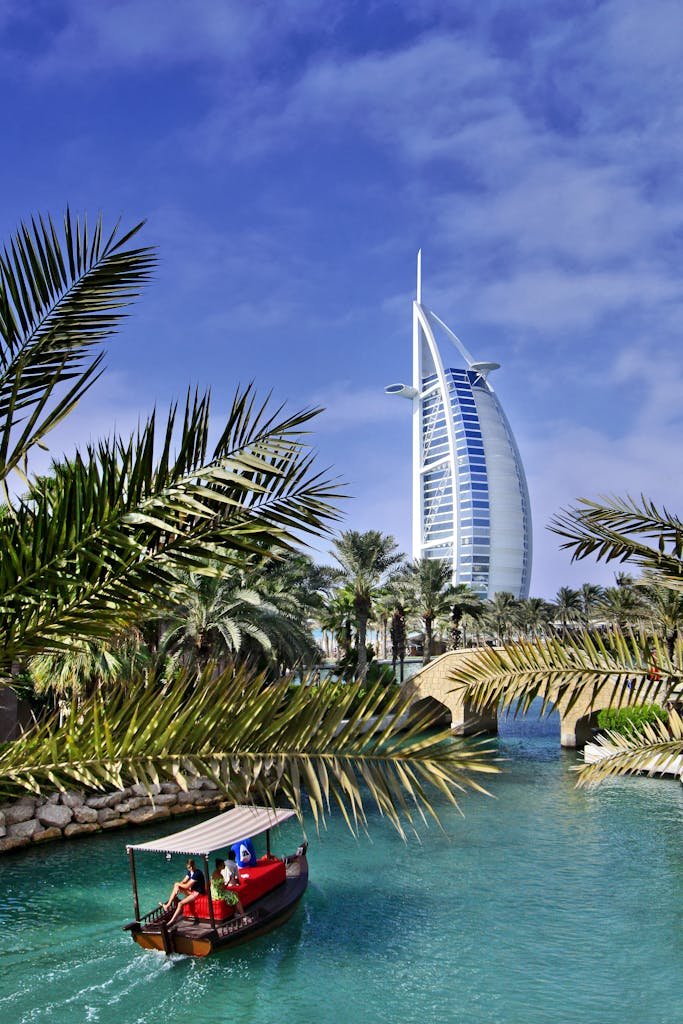 View of Burj Al Arab with tropical plants and traditional boat in Dubai, UAE.