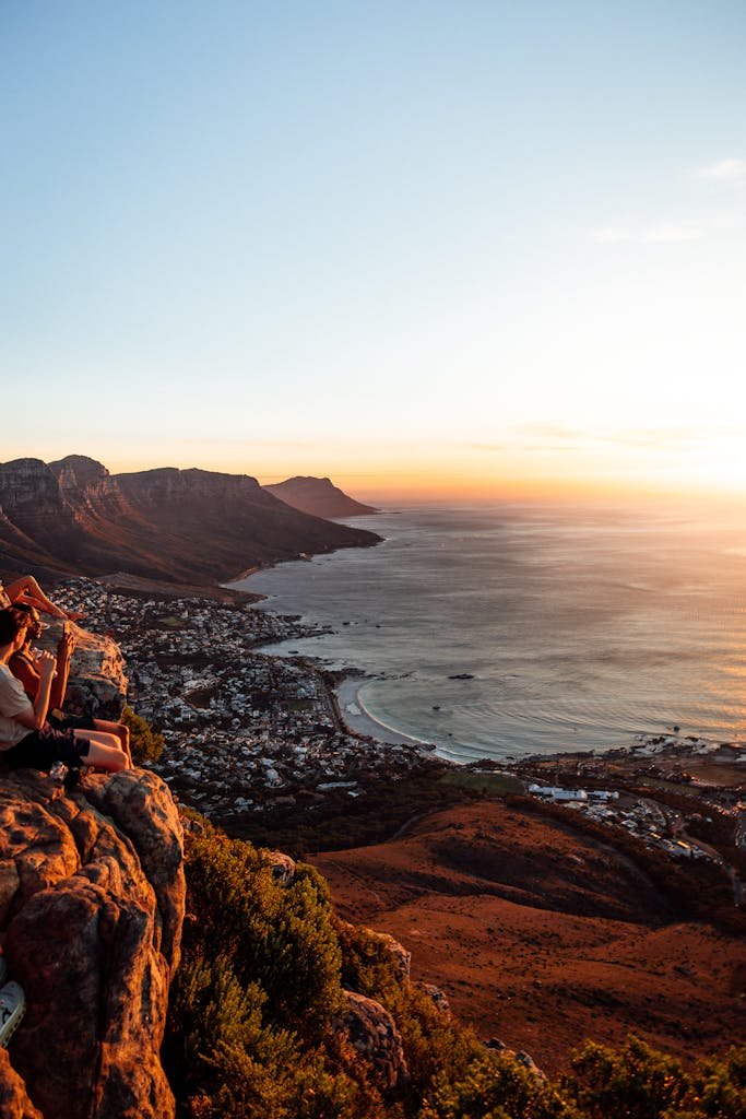 View of Cape Town coastline at sunset with people enjoying the view from a cliff.