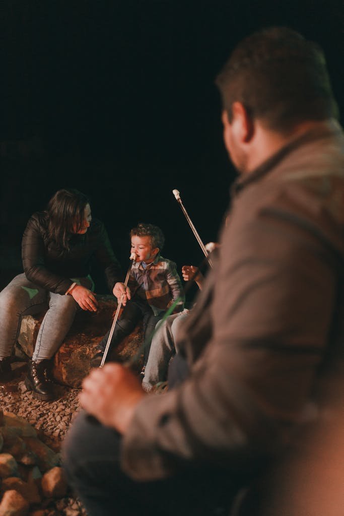 A family enjoys roasting marshmallows over a campfire at night, creating warm memories.