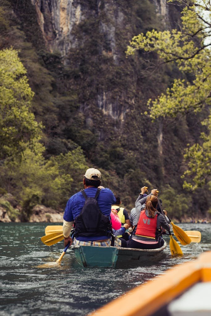 A group of people canoeing through a scenic gorge surrounded by cliffs and greenery.
