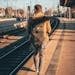 A man with a backpack walks along a train platform, capturing a journey moment in urban daylight.
