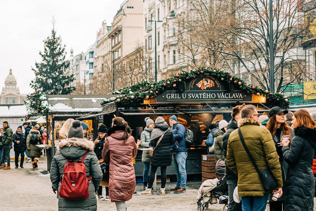 People enjoying a bustling Christmas market in Prague, surrounded by festive decorations.
