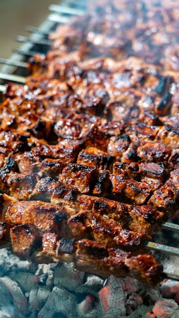 Sizzling and juicy roasted meat skewers grilling over hot charcoal, perfect for a smoky barbecue experience.